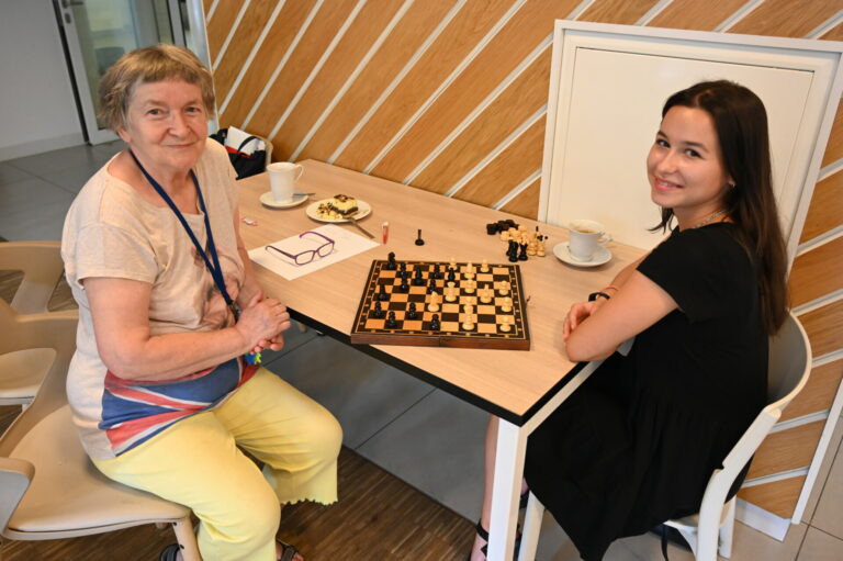 Zdjęcie przedstawia Bywalczynię oraz wolontariuszkę grające w warcaby.