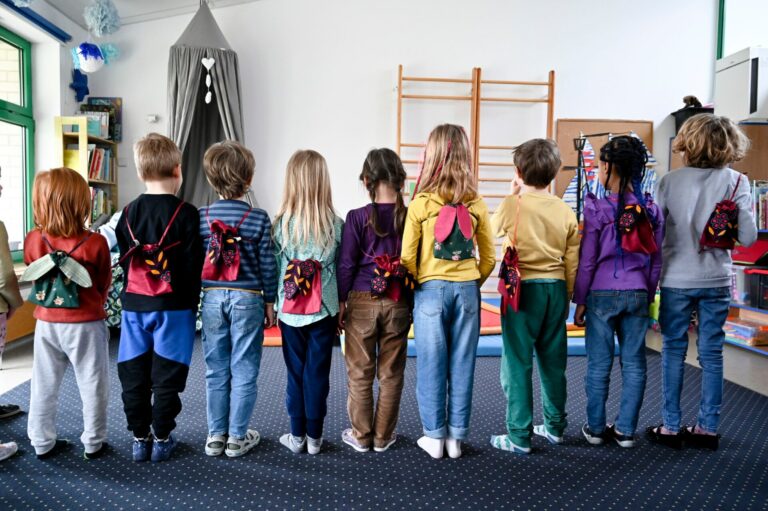 Grupa dzieci w wieku przedszkolnym stoi tyłem prezentując plecaki DIY.
