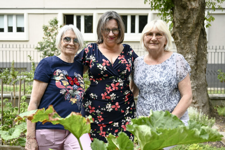 Zdjęcie przedstawia trzy kobiety stojące w ogrodzie.